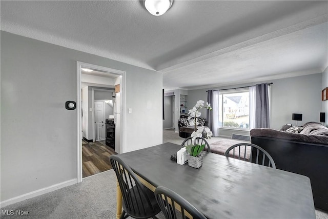 carpeted dining area with baseboards and a textured ceiling