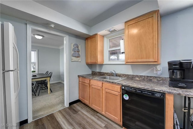 kitchen featuring black dishwasher, dark wood finished floors, dark countertops, freestanding refrigerator, and a sink