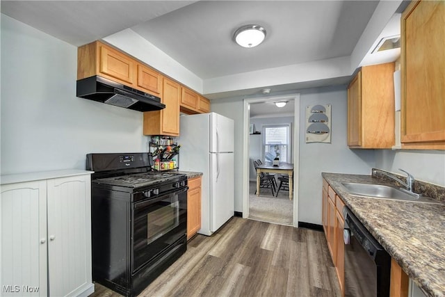 kitchen with dark wood-type flooring, a sink, black appliances, under cabinet range hood, and baseboards