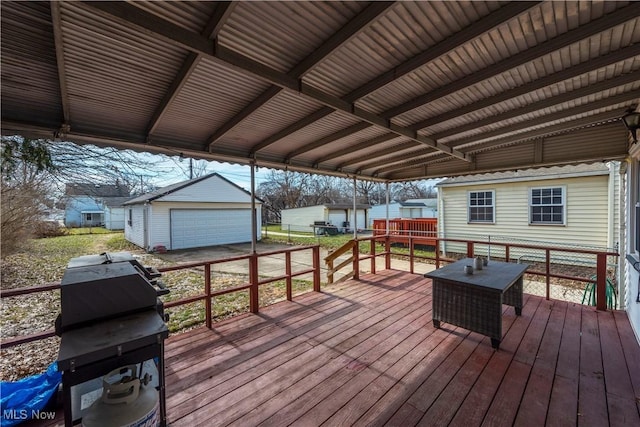 wooden terrace featuring a garage, grilling area, and an outbuilding