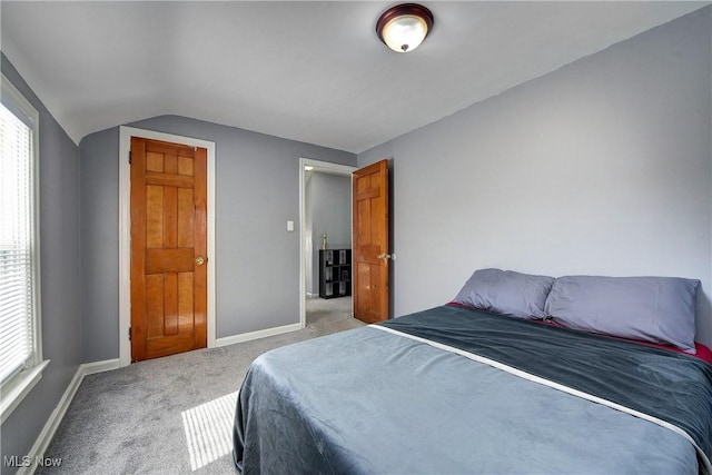 bedroom featuring baseboards, lofted ceiling, and light colored carpet