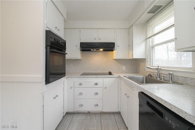 kitchen featuring under cabinet range hood, light countertops, black appliances, white cabinetry, and a sink