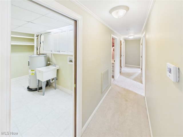 corridor featuring electric water heater, light carpet, visible vents, baseboards, and ornamental molding