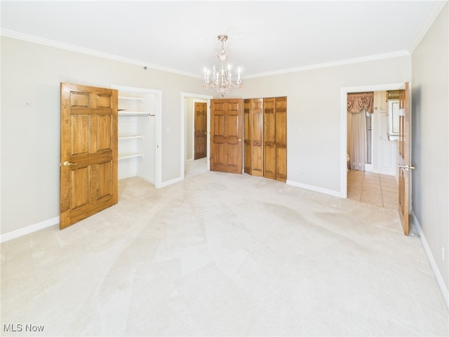 unfurnished bedroom featuring light colored carpet, crown molding, a spacious closet, and baseboards