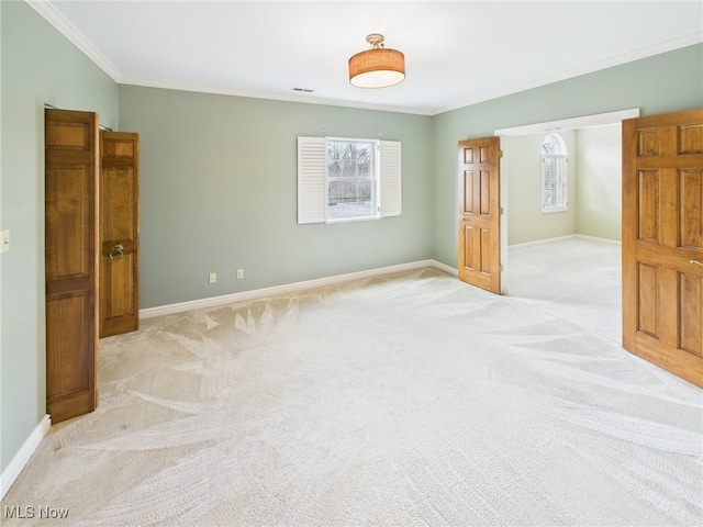 spare room featuring ornamental molding, plenty of natural light, and light colored carpet