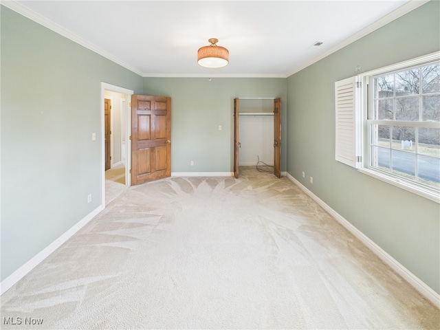 unfurnished bedroom featuring crown molding, a closet, light colored carpet, a spacious closet, and baseboards