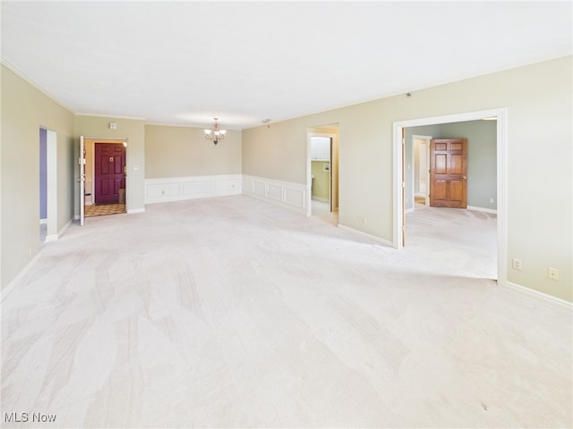 unfurnished room featuring light carpet, a decorative wall, and a notable chandelier