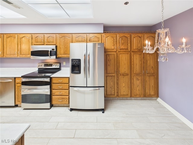 kitchen featuring baseboards, visible vents, brown cabinets, stainless steel appliances, and light countertops