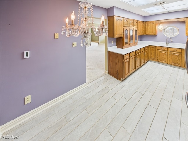 kitchen featuring a skylight, brown cabinets, light countertops, visible vents, and light wood-style flooring