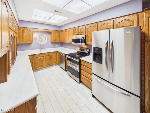 kitchen with stainless steel appliances, a skylight, visible vents, light countertops, and brown cabinets