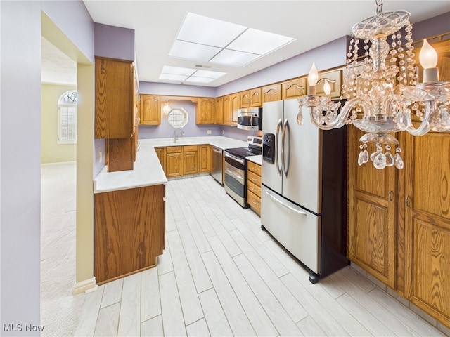 kitchen with a wealth of natural light, light countertops, light wood-style flooring, appliances with stainless steel finishes, and brown cabinetry