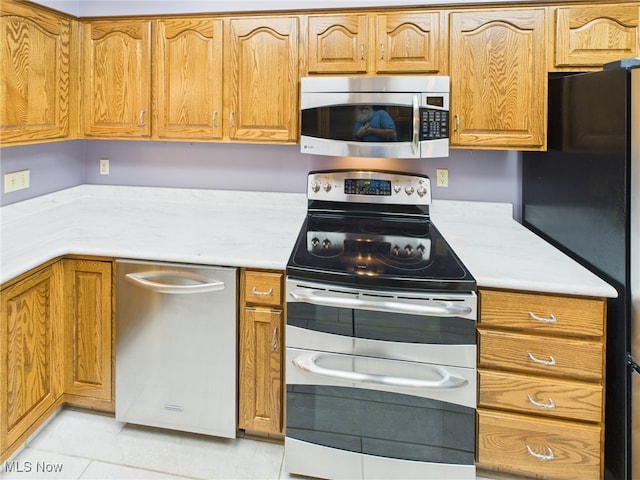 kitchen featuring stainless steel appliances, light tile patterned flooring, light countertops, and brown cabinets