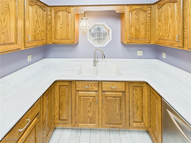 kitchen with brown cabinets, dishwasher, light countertops, and a sink