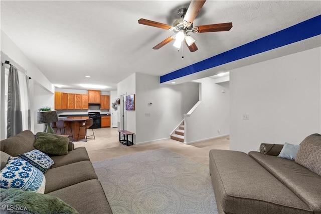 living area featuring stairs, baseboards, a ceiling fan, and light colored carpet