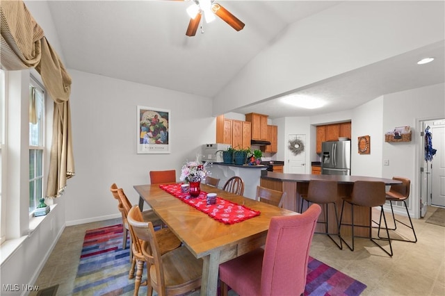 dining space with vaulted ceiling, a ceiling fan, and baseboards