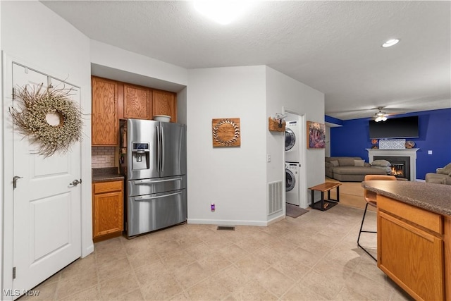 kitchen with brown cabinets, stacked washer / dryer, and stainless steel fridge