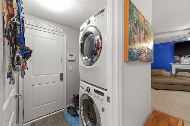 laundry room featuring stacked washer / drying machine, laundry area, ceiling fan, and a textured ceiling