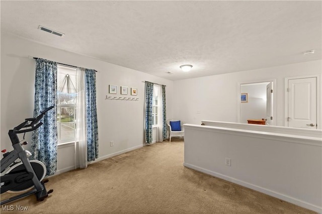 interior space featuring baseboards, visible vents, and light colored carpet