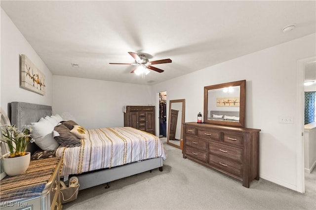 bedroom with a ceiling fan, light colored carpet, connected bathroom, and baseboards