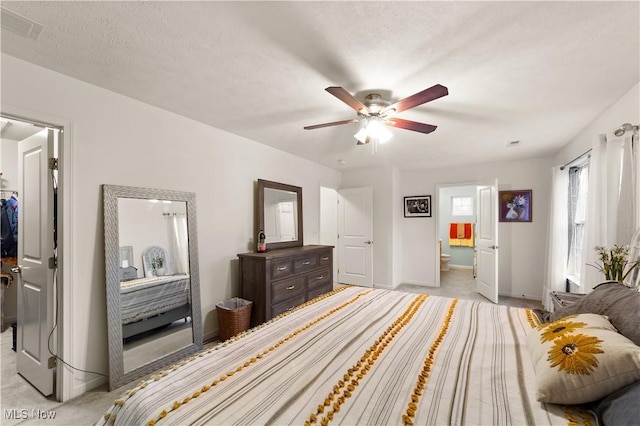 bedroom with a walk in closet, light colored carpet, visible vents, connected bathroom, and baseboards