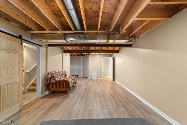 finished basement with a barn door, wood finished floors, and baseboards