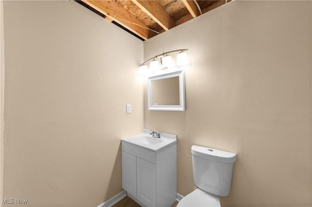 half bath with toilet, baseboards, and vanity