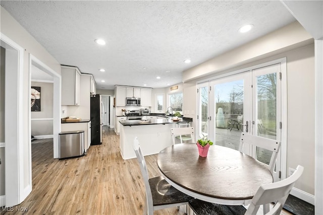 kitchen featuring recessed lighting, dark countertops, appliances with stainless steel finishes, light wood-style floors, and a textured ceiling