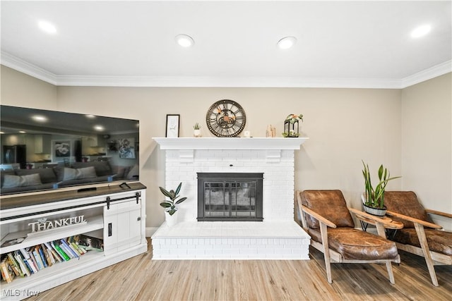 living room featuring ornamental molding, a brick fireplace, wood finished floors, and recessed lighting