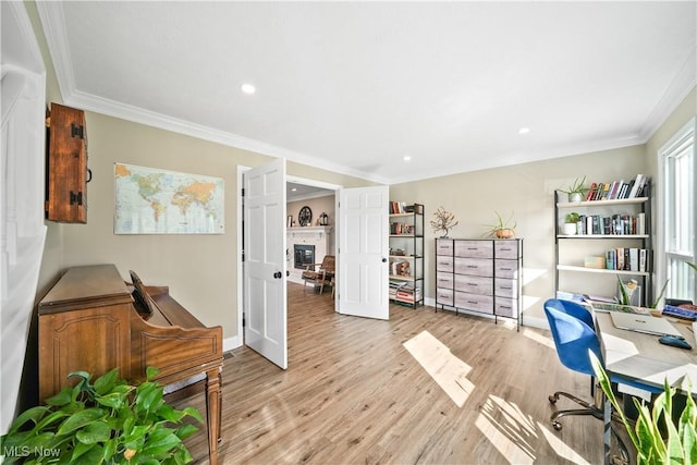 office area featuring baseboards, a glass covered fireplace, light wood-style flooring, crown molding, and recessed lighting