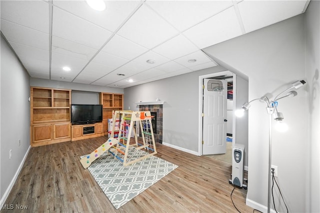 playroom with baseboards, a tiled fireplace, and wood finished floors