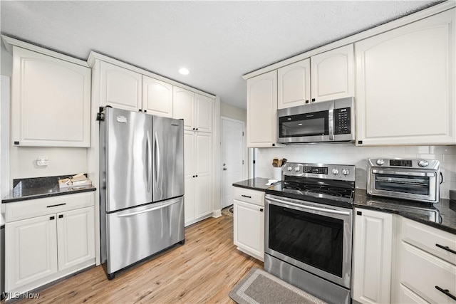 kitchen with light wood-style flooring, a toaster, stainless steel appliances, white cabinets, and tasteful backsplash