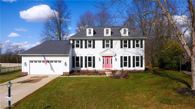 colonial-style house featuring a shingled roof, concrete driveway, an attached garage, fence, and a front lawn