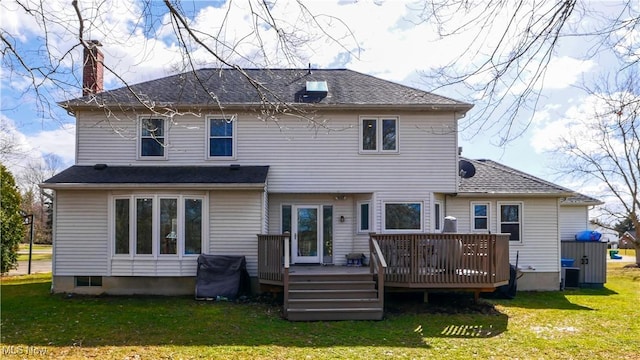 back of house featuring a chimney, a deck, and a lawn