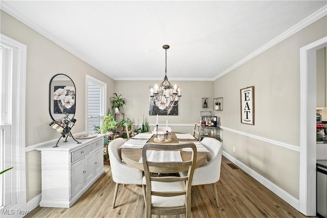 dining space with light wood finished floors, baseboards, ornamental molding, and an inviting chandelier