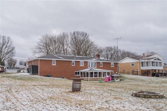 back of house featuring an outdoor fire pit, brick siding, and a chimney