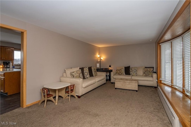 carpeted living area with baseboards and a baseboard heating unit