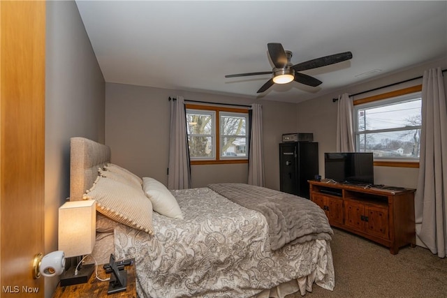 carpeted bedroom with visible vents, multiple windows, and a ceiling fan