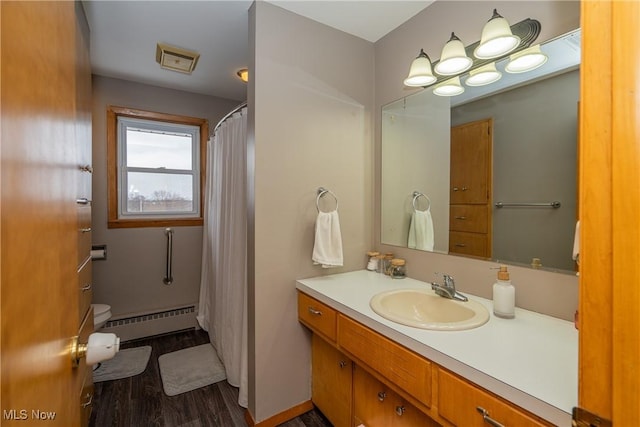 bathroom with a shower with shower curtain, toilet, a baseboard heating unit, vanity, and wood finished floors