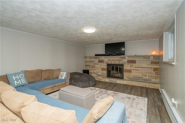 living room with a baseboard heating unit, a fireplace, a textured ceiling, and wood finished floors