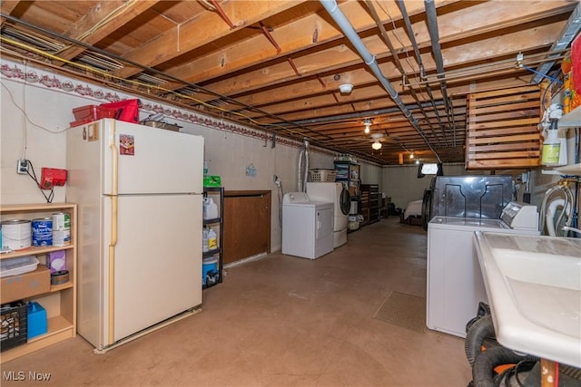 basement featuring a sink, washer and dryer, and freestanding refrigerator