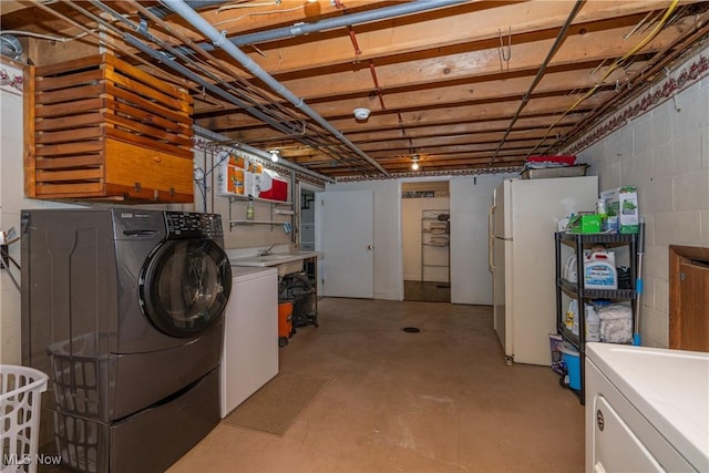 unfinished below grade area with concrete block wall, separate washer and dryer, and freestanding refrigerator