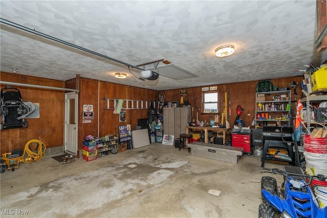 garage with wood walls, a workshop area, and a garage door opener