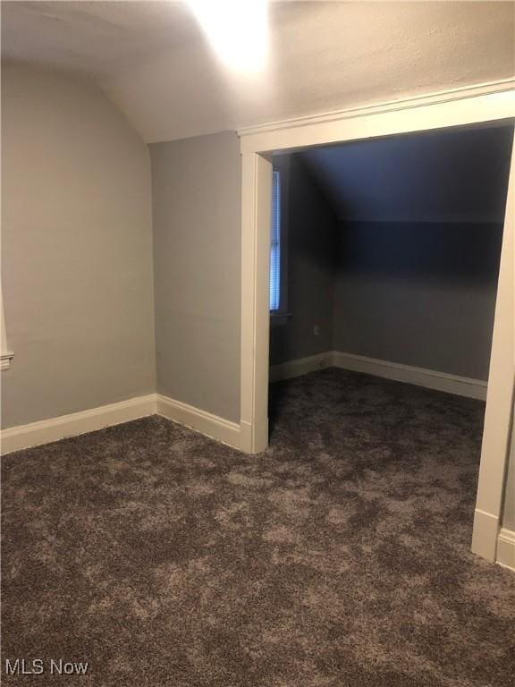 bonus room featuring lofted ceiling, baseboards, and dark colored carpet