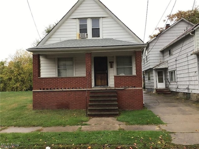 bungalow with entry steps, covered porch, a shingled roof, and brick siding