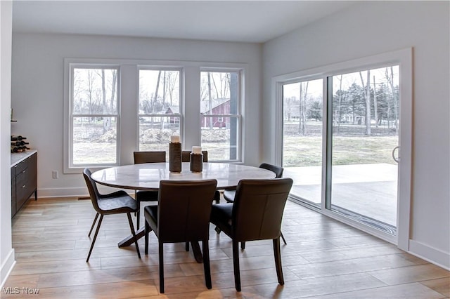 dining space with a healthy amount of sunlight, light wood-style flooring, and baseboards