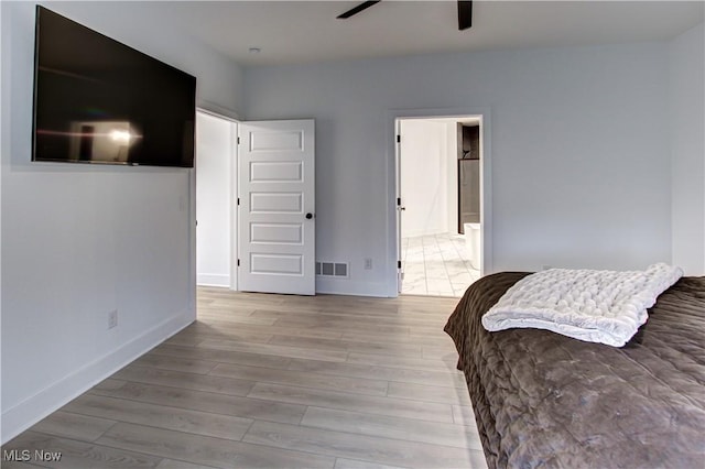 bedroom featuring light wood finished floors, visible vents, ensuite bathroom, a ceiling fan, and baseboards