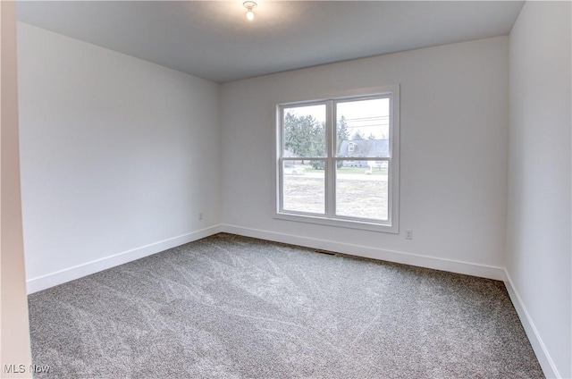 carpeted empty room with visible vents and baseboards