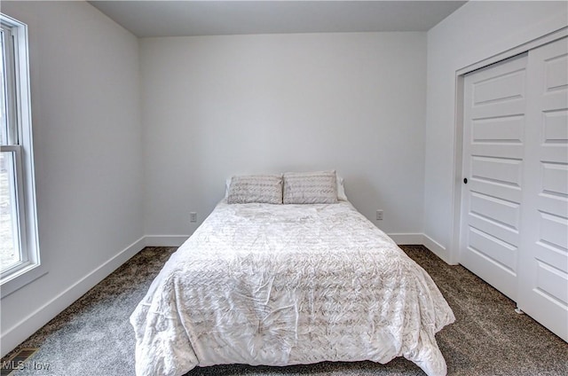 bedroom with baseboards, dark colored carpet, and a closet