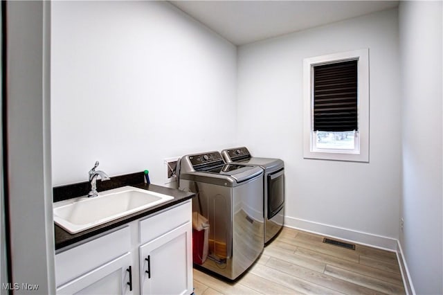 laundry room featuring cabinet space, visible vents, light wood-style floors, a sink, and separate washer and dryer