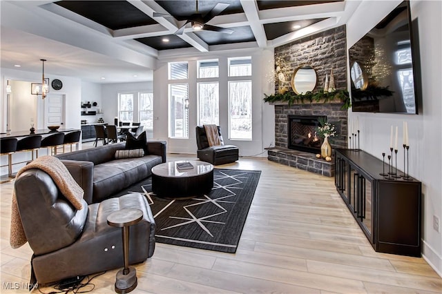 living area featuring beam ceiling, a fireplace, light wood finished floors, recessed lighting, and coffered ceiling